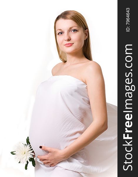 Pregnant woman in the white drapery with white flower. Pregnant woman in the white drapery with white flower