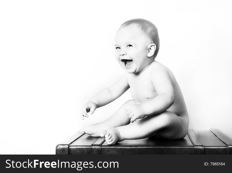 Young baby sitting on an old style suitcase