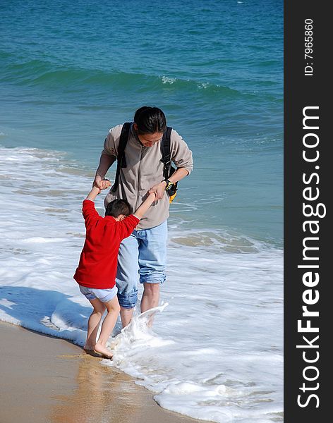 Father and son playing in the surfy beach