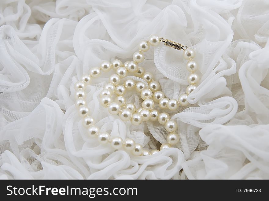Pearl necklace with white ruffles in the background. Pearl necklace with white ruffles in the background.