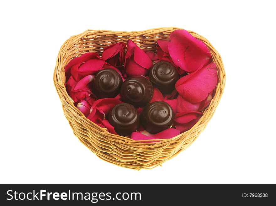 Red rose petals and liquer chocolates in a heart shaped basket. Red rose petals and liquer chocolates in a heart shaped basket