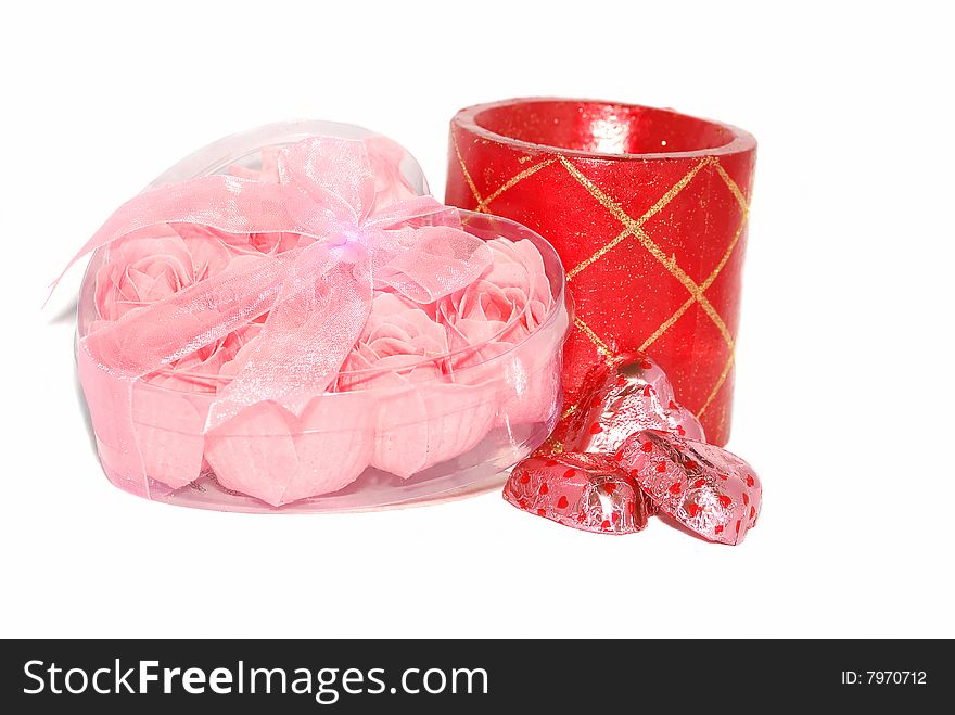 Pink little roses are in the plastic heart box with red candle and chocolate sweets. Pink little roses are in the plastic heart box with red candle and chocolate sweets.