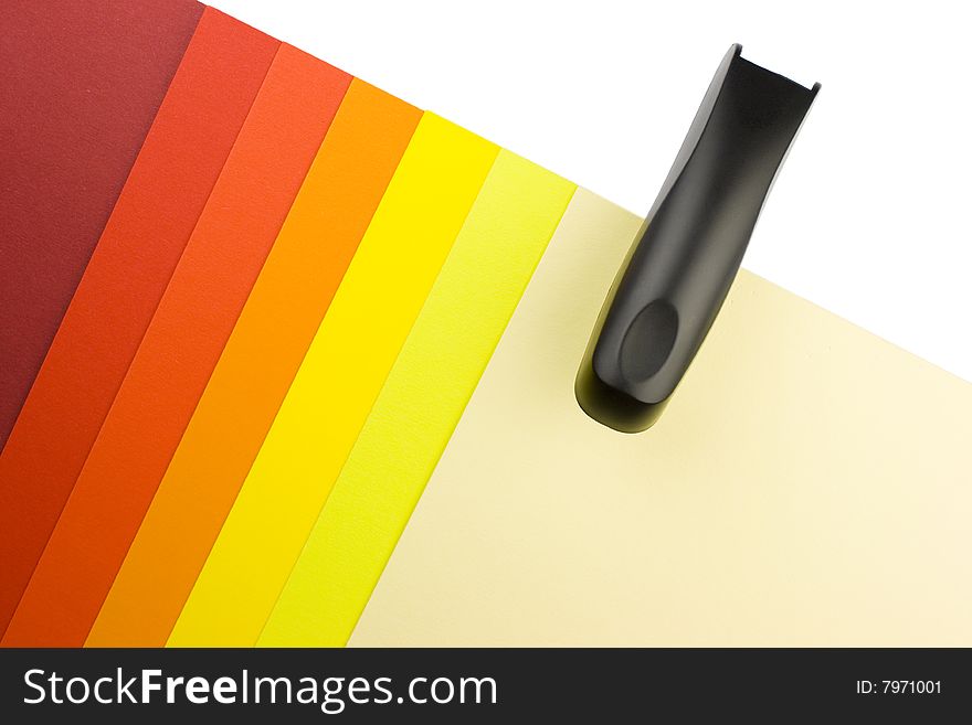 Colorful paper sheets in warm tones - yellow, orange and red - with a black paper stapler. Colorful paper sheets in warm tones - yellow, orange and red - with a black paper stapler.