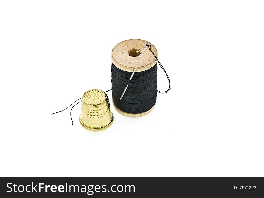 A spool of thread with a needle in it and thimble
on white