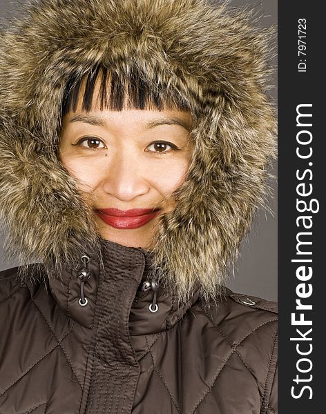 Asian woman dressed in a winter coat with fur hood.