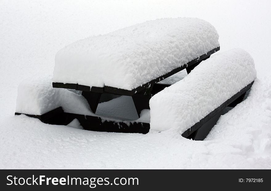 Picnic table covered with inches of snow. Picnic table covered with inches of snow