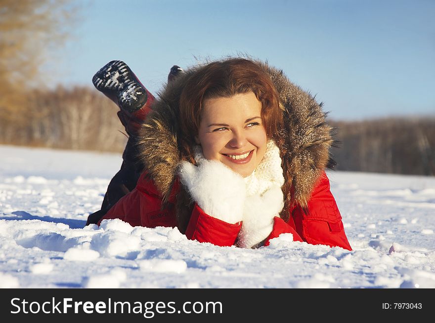 attractive girl lays on white snow and smiles