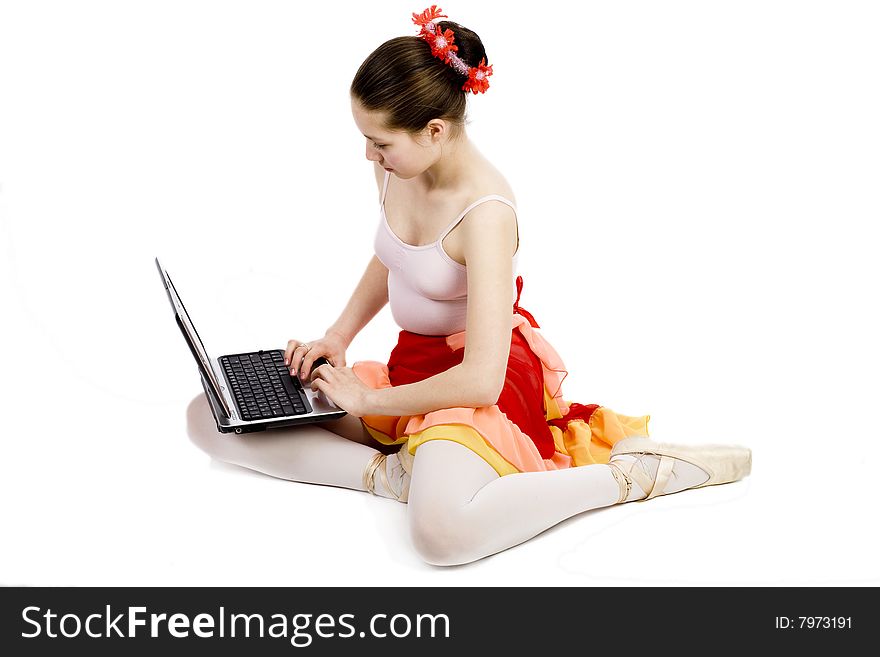 Young ballerina sits on floor with computer