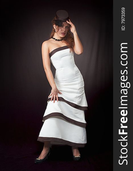 The young beautiful girl in a white smart evening dress on a black background. The young beautiful girl in a white smart evening dress on a black background