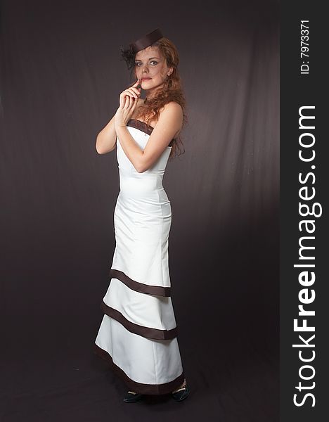 The young beautiful girl in a white smart evening dress on a black background. The young beautiful girl in a white smart evening dress on a black background