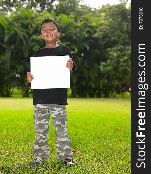 Boy with a blank placard in the garden