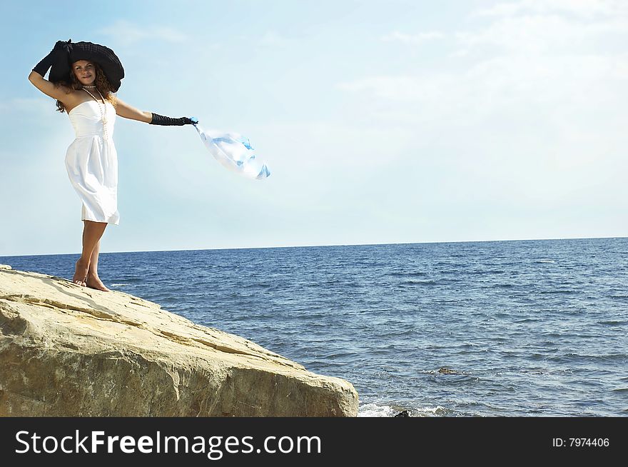 girl in a black hat holds headscarf on a wind