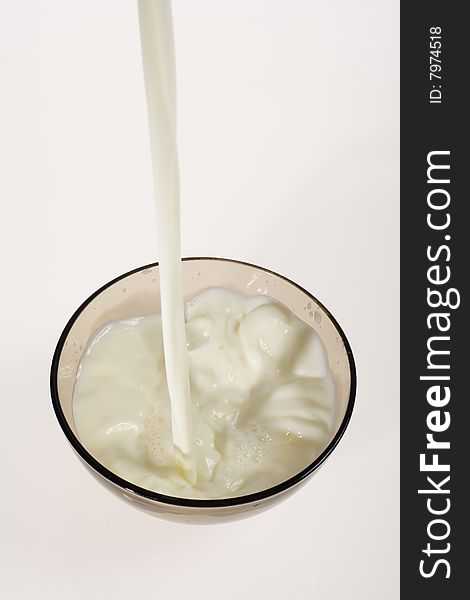 Pouring milk into glass bowl on white background. Pouring milk into glass bowl on white background