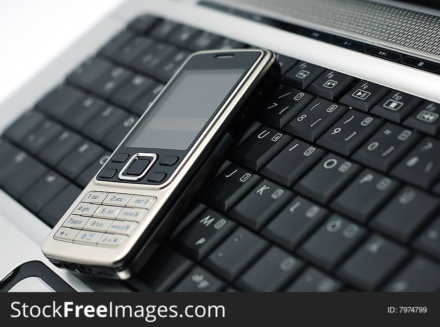 Mobile phone on a laptop with white background