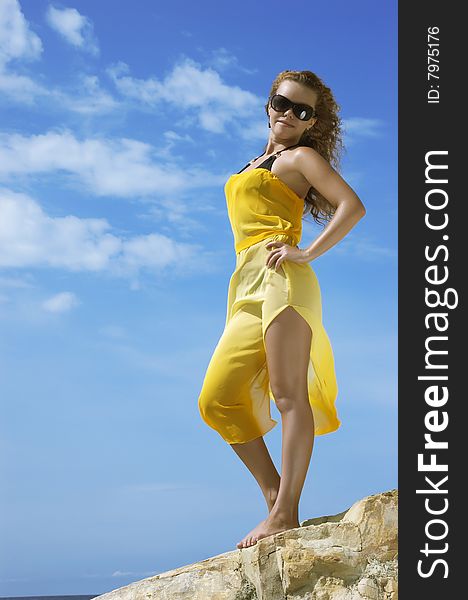 The beautiful young woman on a stone beach in a yellow dress. The beautiful young woman on a stone beach in a yellow dress