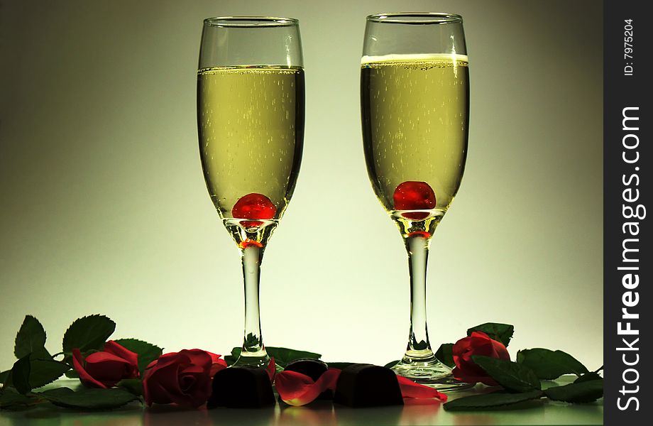 Two glasses of champagne, cherries, chocolate, roses and romantic lighting. Two glasses of champagne, cherries, chocolate, roses and romantic lighting.