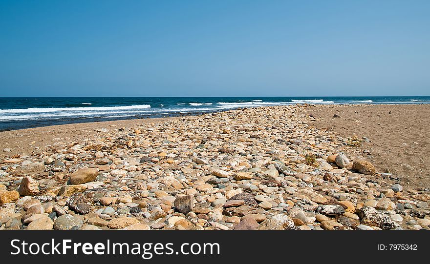 A deserted pebble beach with waves breaking on the shore.