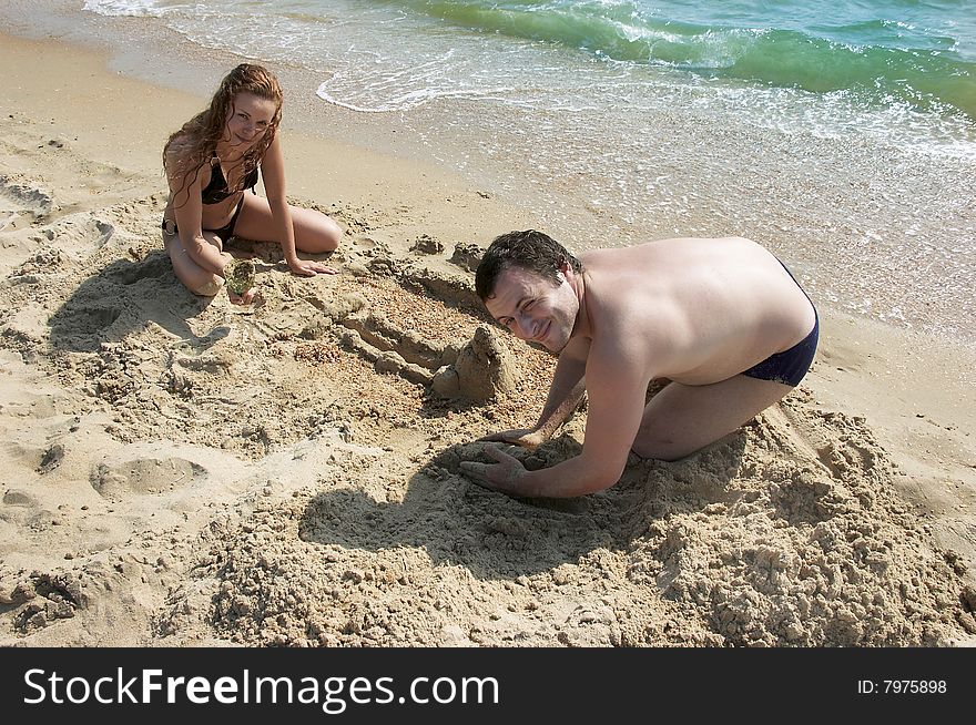 The beautiful man and woman play sand. The beautiful man and woman play sand