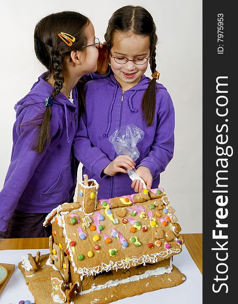 Twins decorating a gingerbread house