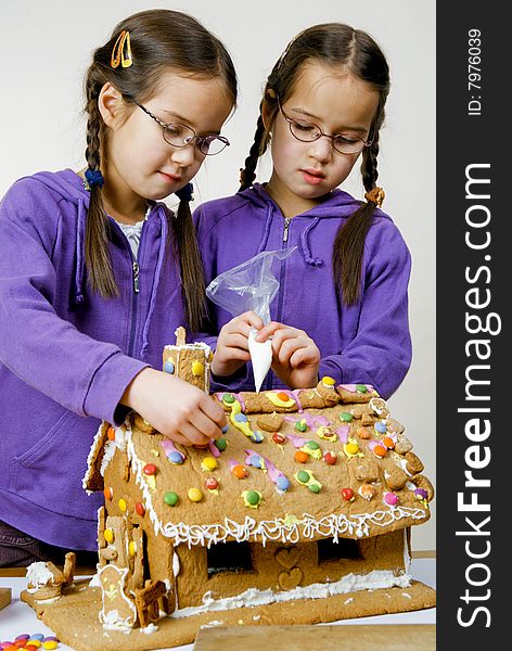 Twins decorating a gingerbread house