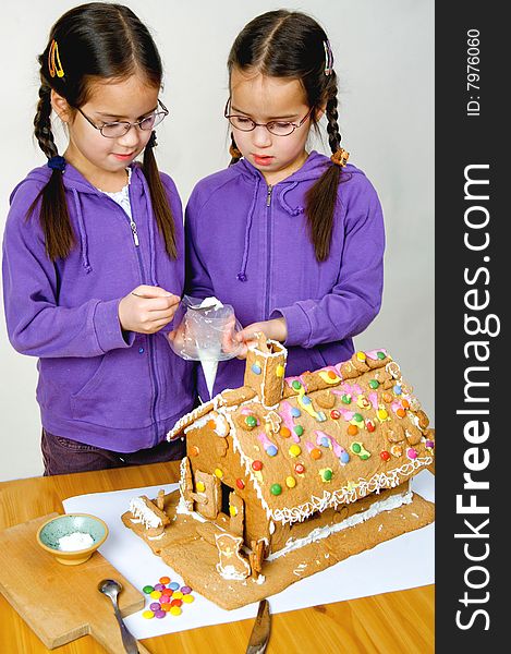 Twins decorating a gingerbread house