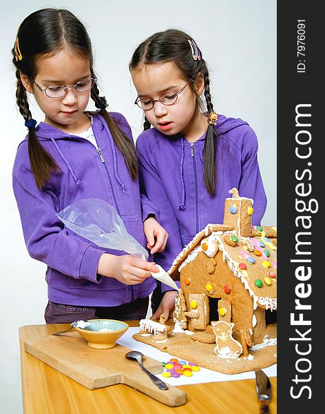 Twins decorating a gingerbread house
