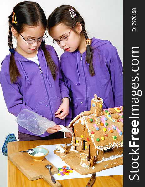 Twins decorating a gingerbread house