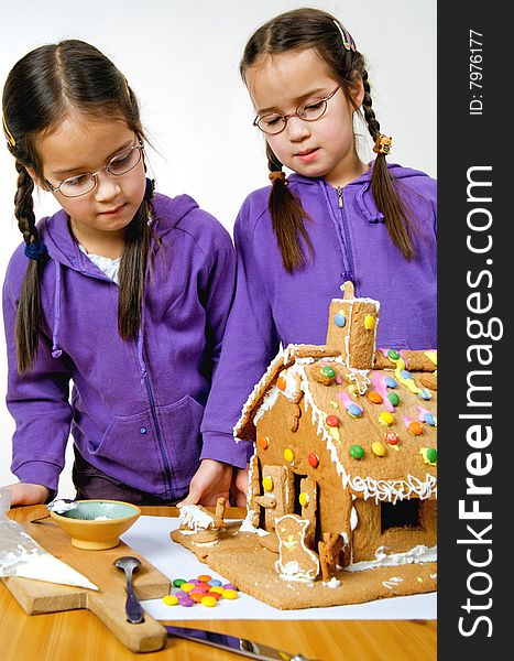 Twins decorating a gingerbread house