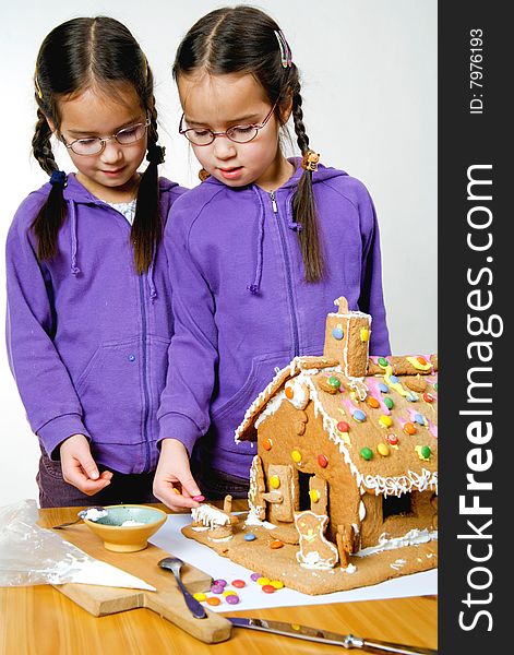 Twins decorating a gingerbread house