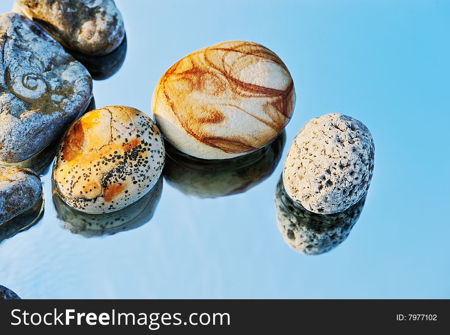 The sea pebble is reflected in a mirror in the summer at midday. The sea pebble is reflected in a mirror in the summer at midday