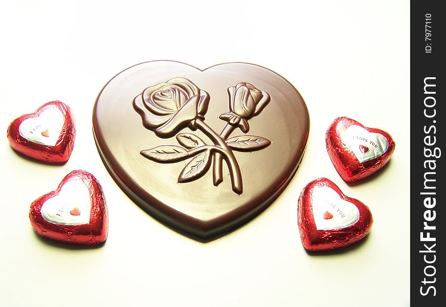Heart and lips chocolates wrapped in red paper and a big heart chocolate with embossed flowers on it