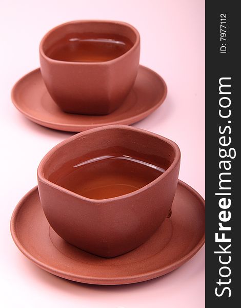 Two cups of tea are on the white and pink background. This is traditional Chinese tea. Two cups of tea are on the white and pink background. This is traditional Chinese tea.