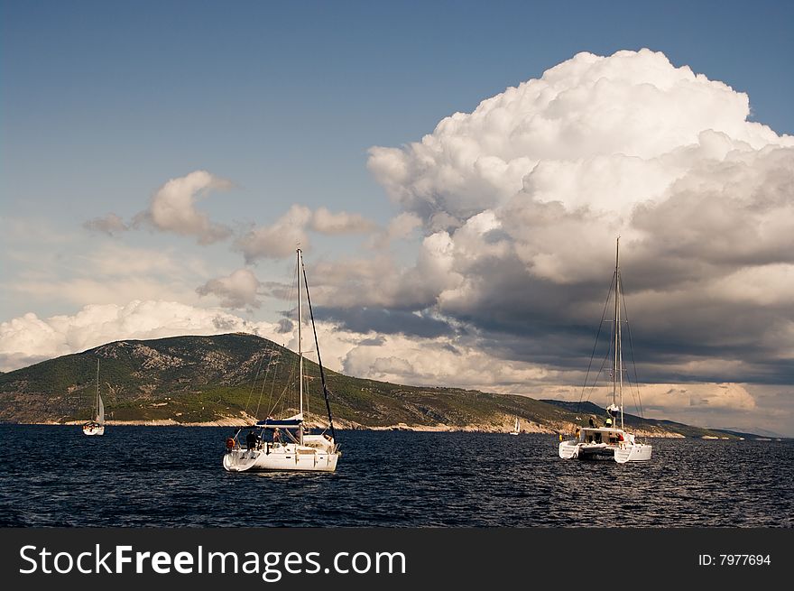 Yachts sailing near shore under dramatic sky in Croatia