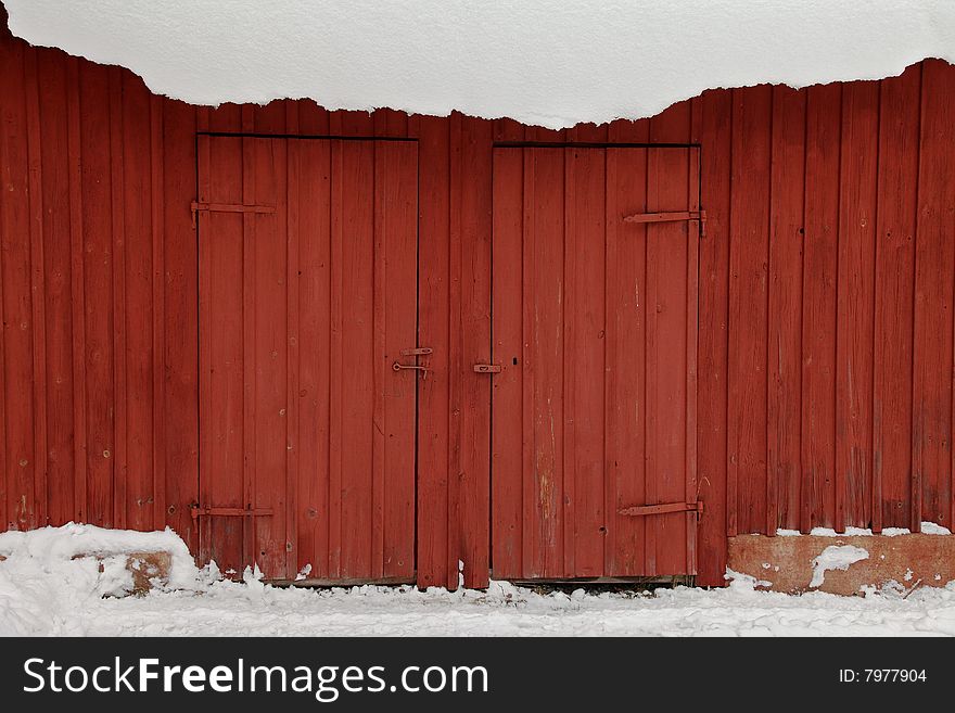 Red shed in winter snow with two red doors