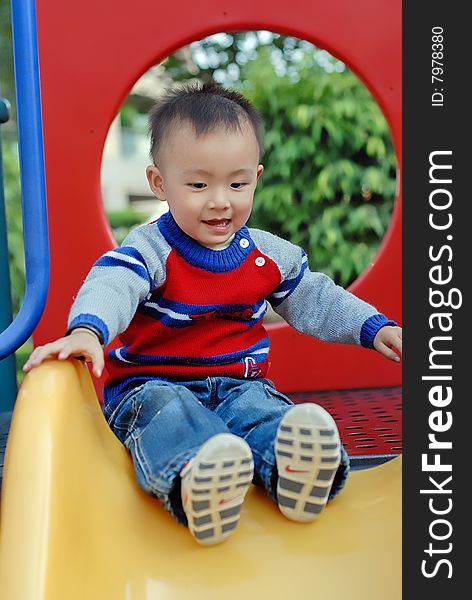 asian boy playing the sliding board