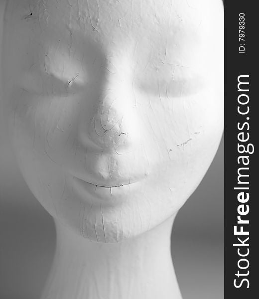 A head of an old female mannequin fashion head painted white, worn and used with cracks and scratches. A head of an old female mannequin fashion head painted white, worn and used with cracks and scratches.