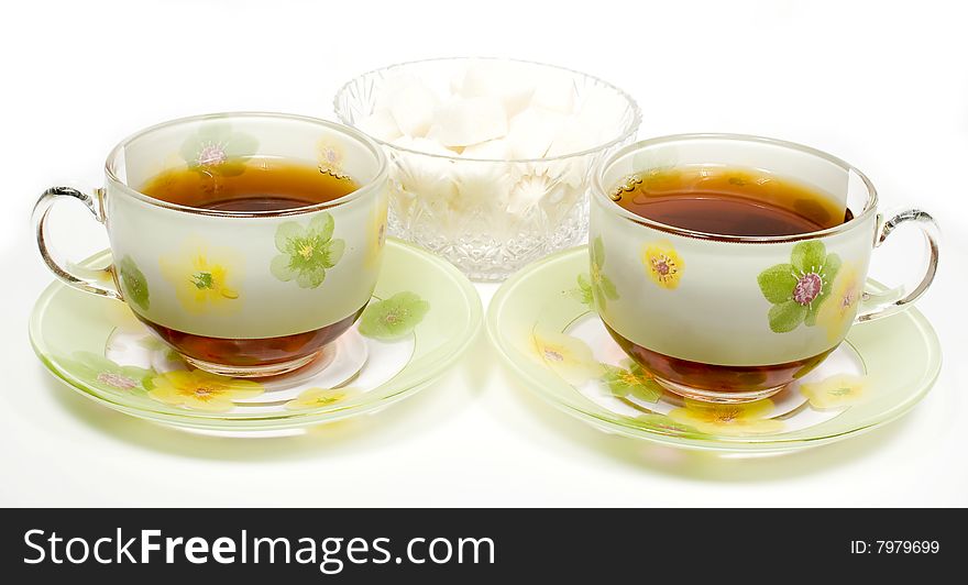 Two tea cups on a saucer with sugar
