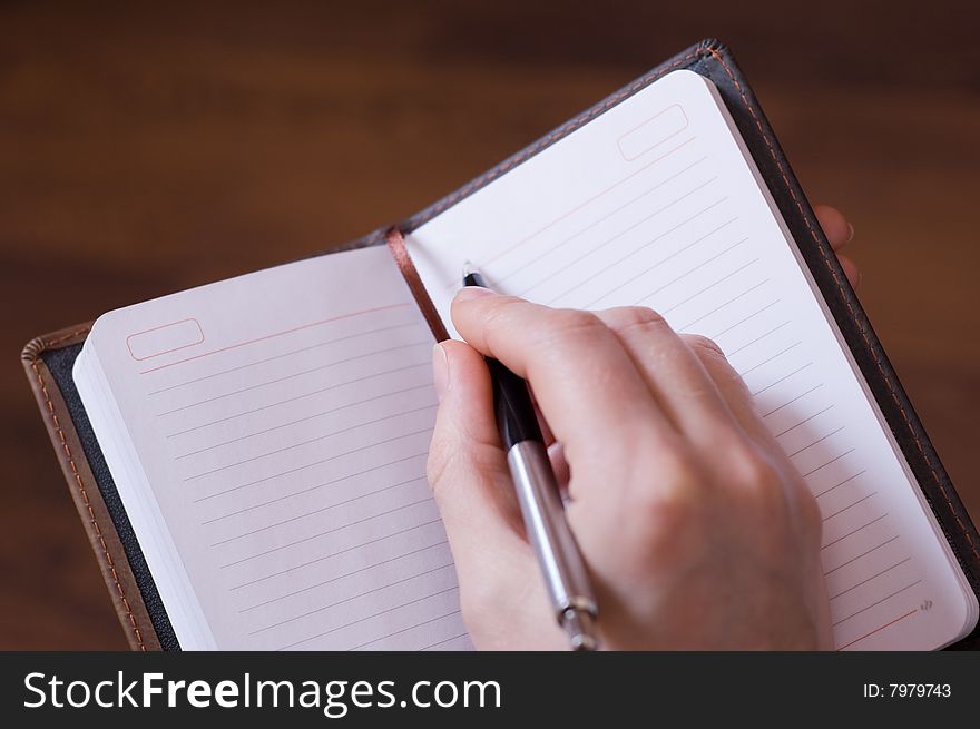 Female writes notes in notebook by pen. Female writes notes in notebook by pen