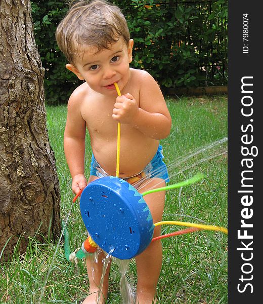 A toddler playing in the backyard with a sprinkler. A toddler playing in the backyard with a sprinkler.