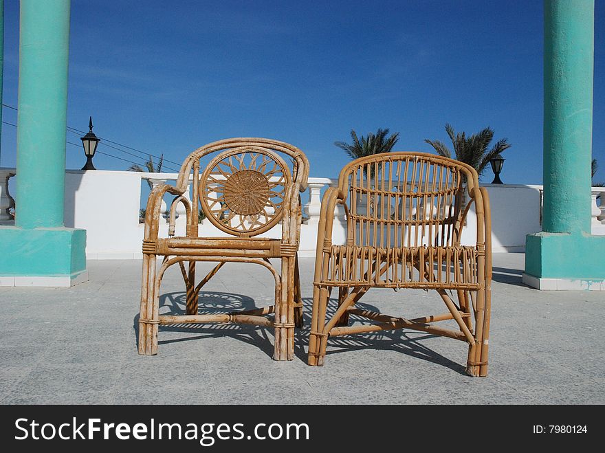 Wattled chairs on a verandah at a sea