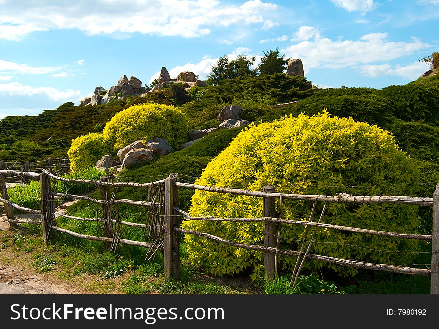 Garden's fence, green trees and stones