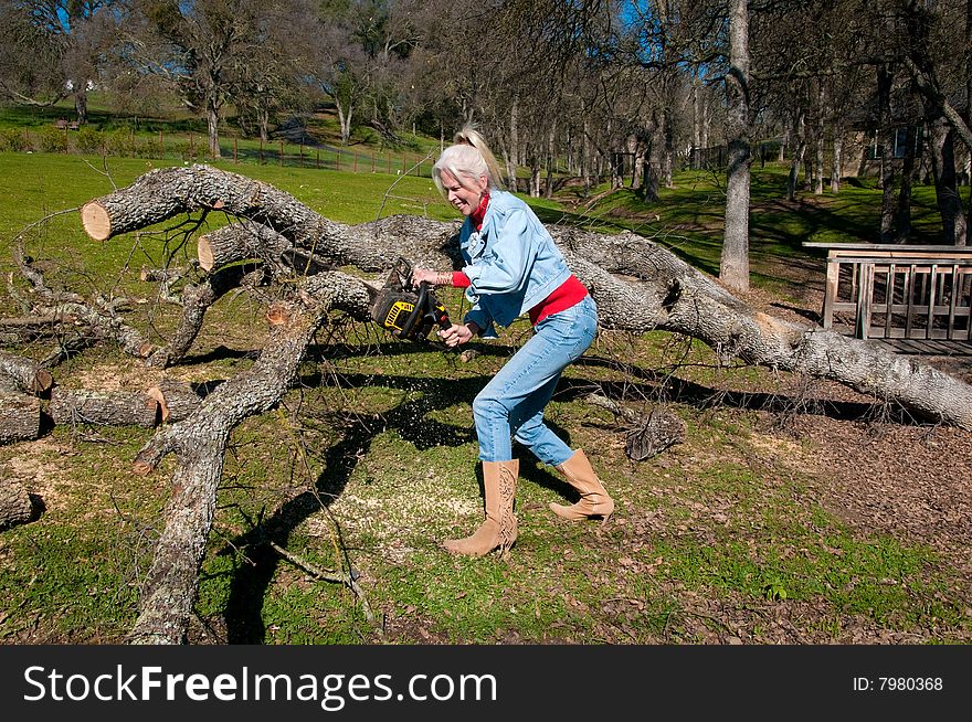 Action capture of an attractive blond female using a chain saw to cut up a large downed oak tree. Action capture of an attractive blond female using a chain saw to cut up a large downed oak tree.