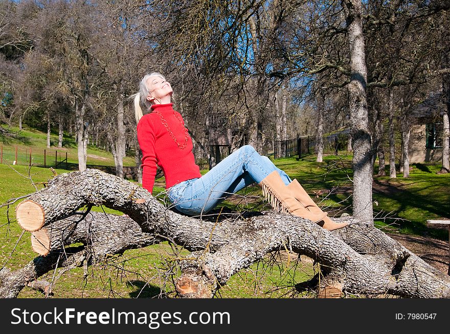 Attractive blond girl sitting on downed oak tree. Attractive blond girl sitting on downed oak tree.