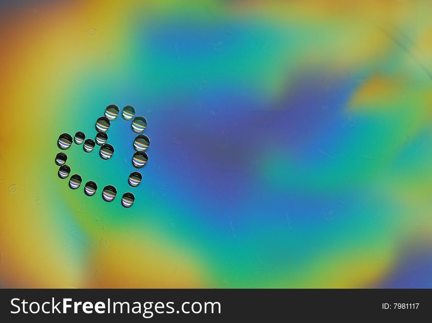 Heart from drops of water on a color surface