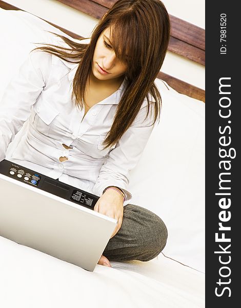 Young smiling businesswoman using laptop in bed. Young smiling businesswoman using laptop in bed