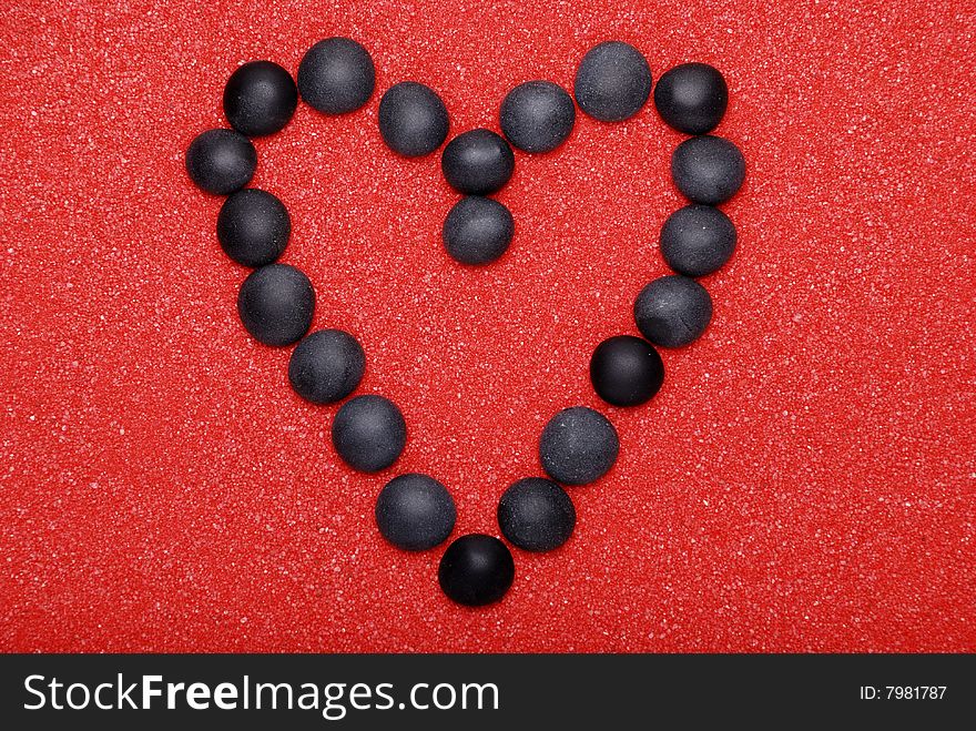 Black heart from stones on red sand. Black heart from stones on red sand