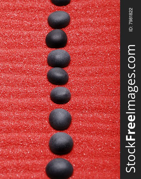Line from black stones on red sand