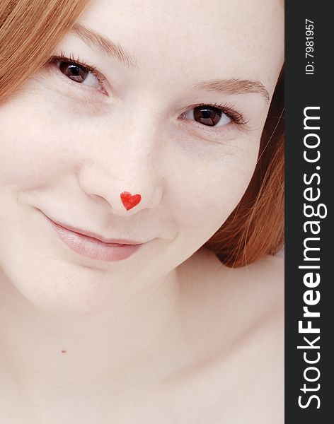 Portrait of the redhead young woman with heart on the nose