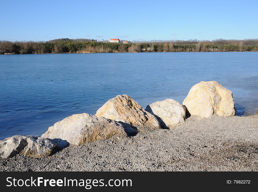 Frozen lake in winter with blue sky and rocks. Frozen lake in winter with blue sky and rocks