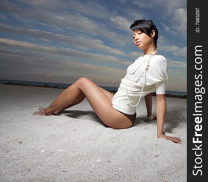 Beautiful young woman sitting on the sand. Beautiful young woman sitting on the sand